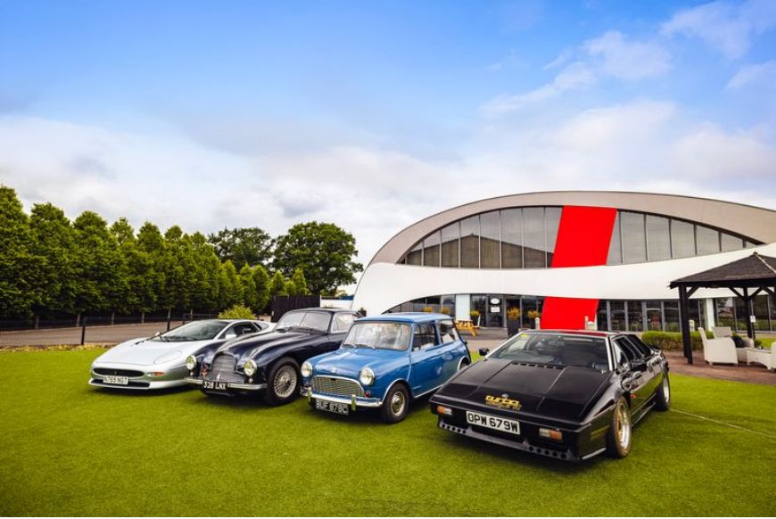 4 cars on a green lawn next to building
